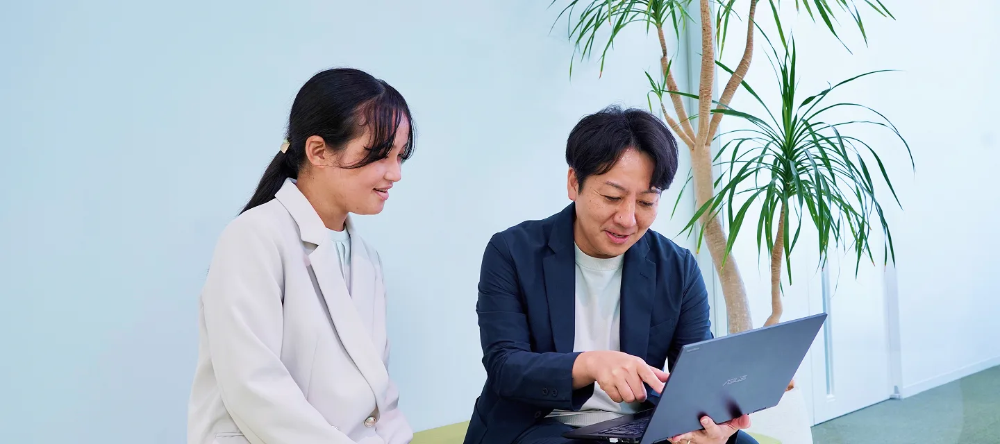 ノートパソコンを見ながら話す社員